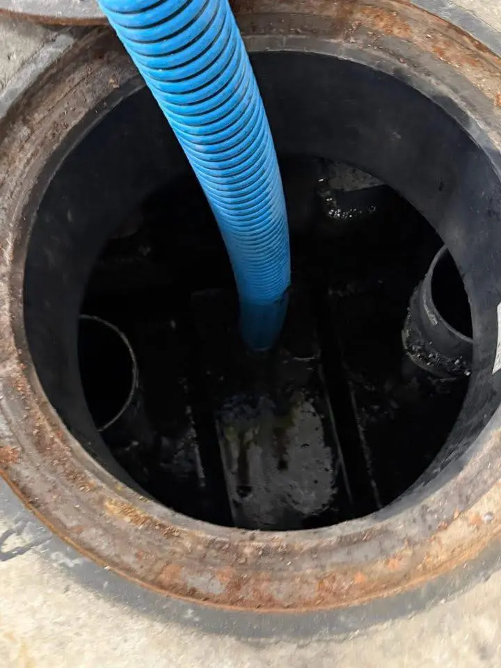 Vacuum hose pumping out an open septic tank