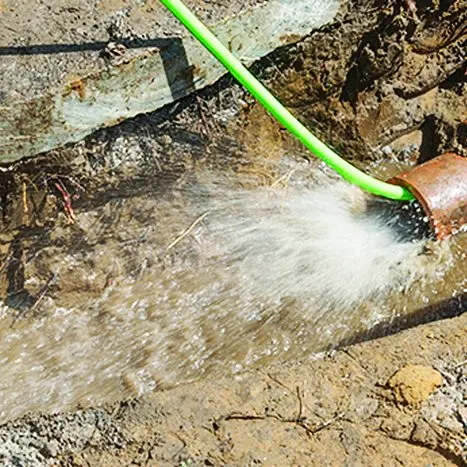 High-pressure water flushing a line during sewer jetting