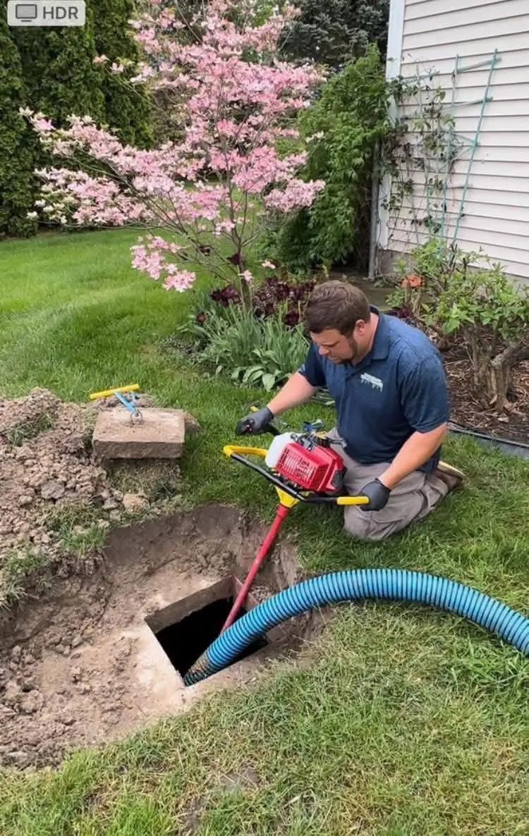 Technician working a hose at an excavated septic access point